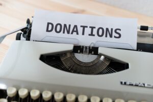 typewriter showing a piece of paper with donations written